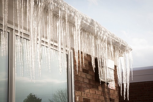Gutters filled with an ice dam and large icicles hanging