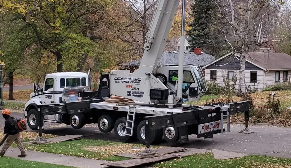 A large National Crane boom truck set up on outriggers for a residential tree removal