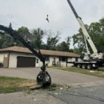 Grapple loader collecting cut branches beside the crane during tree removal work in Blaine