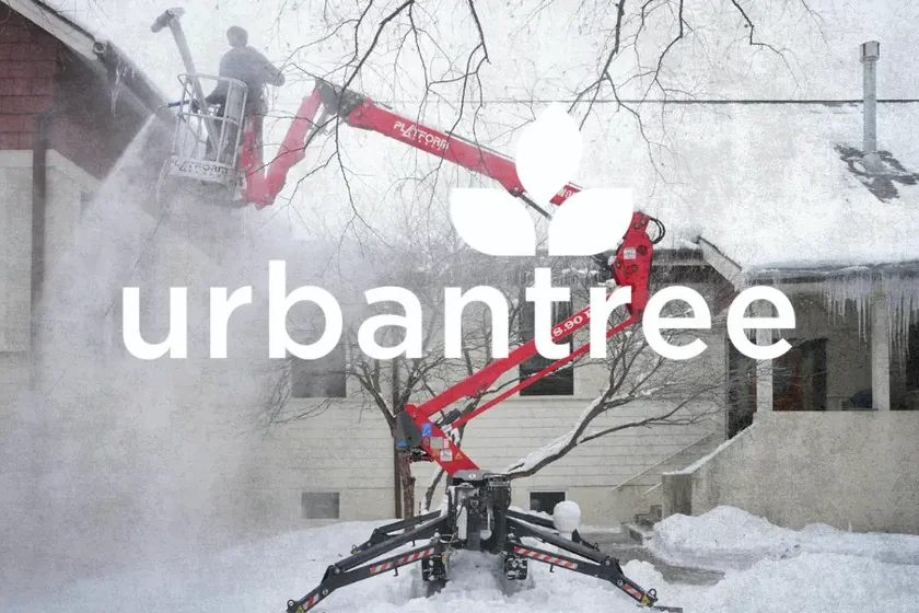 An Urban Tree operator steaming an ice dam off a roof from a tracked spider lift, working the dam down section by section